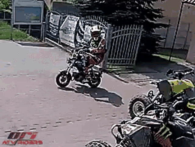 a man is riding a motorcycle down a street next to a row of atv 's .
