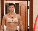 a shirtless man wearing a bra and a necklace is standing in front of a door .