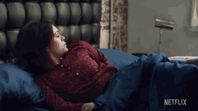 a woman is laying in bed with a netflix logo on the bottom right