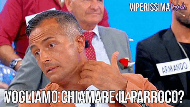 a man with a name tag that says armando sits in a crowd of people