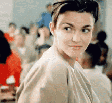 a woman with short hair is looking at the camera with a crowd in the background
