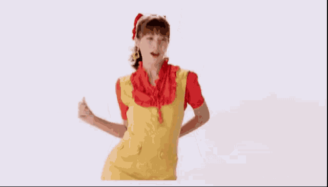 a woman in a yellow apron and red shirt is dancing .