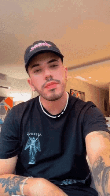 a man wearing a black t-shirt with a picture of an angel on it and a black hat with the word swag on it