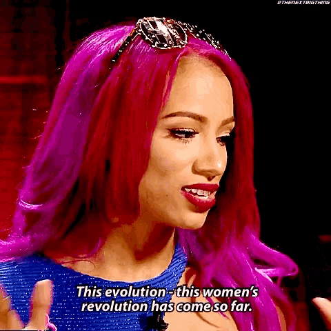 a woman with purple hair is wearing sunglasses and a blue dress .