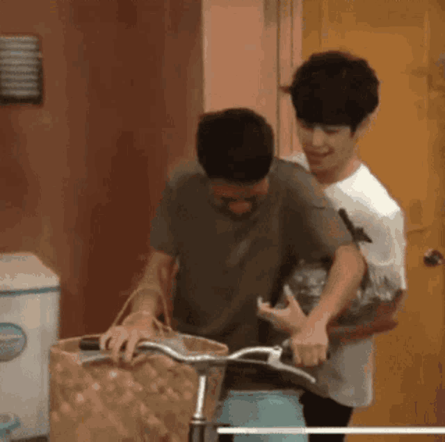 two men are standing next to each other holding a bicycle