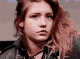 a young woman with long hair is making a funny face .