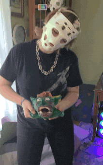 a woman wearing a mask and a necklace is holding a frog in her hands