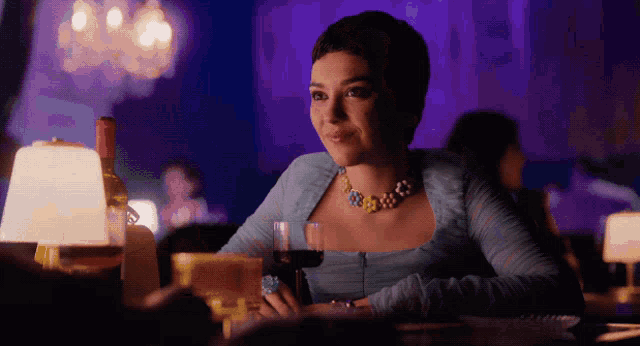 a woman sitting at a table with a glass of wine and a bottle of wine