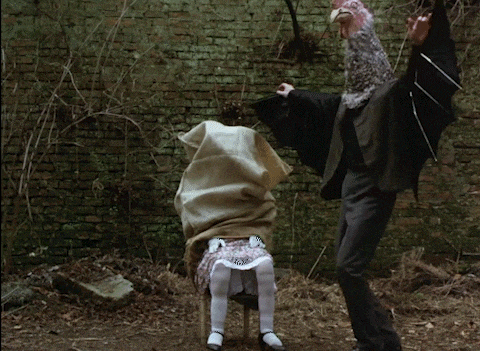 a person with a bat on their head is standing next to a child in a chair