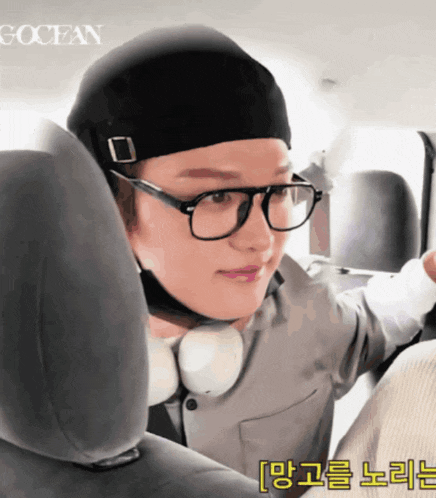 a man wearing glasses and a hat is sitting in the back seat of a car with the word ocean on the bottom right