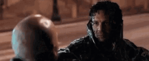 a man is covered in venom while talking to another man .