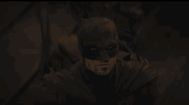 a close up of a man wearing a batman mask in a dark room