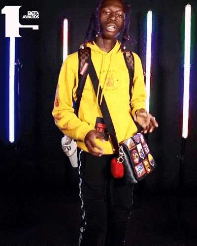 a man in a yellow hoodie stands in front of a bet awards sign