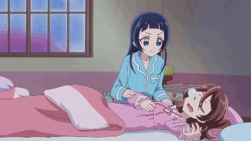 two anime girls are laying on a bed with a pink blanket