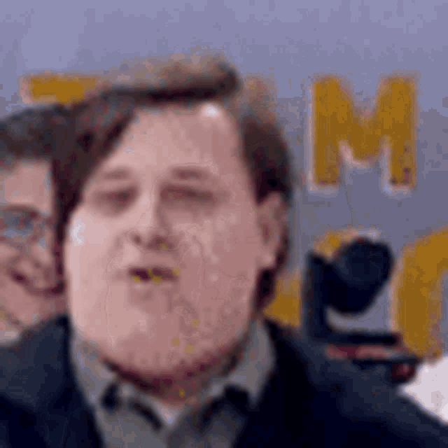 a man is making a funny face in front of a sign that says tm .