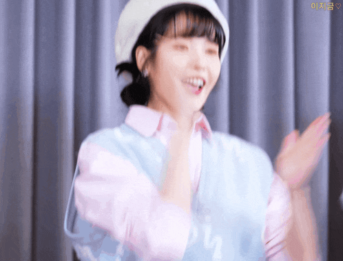 a woman wearing a pink shirt and a white hat is clapping