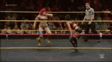 two women are wrestling in a ring with a referee