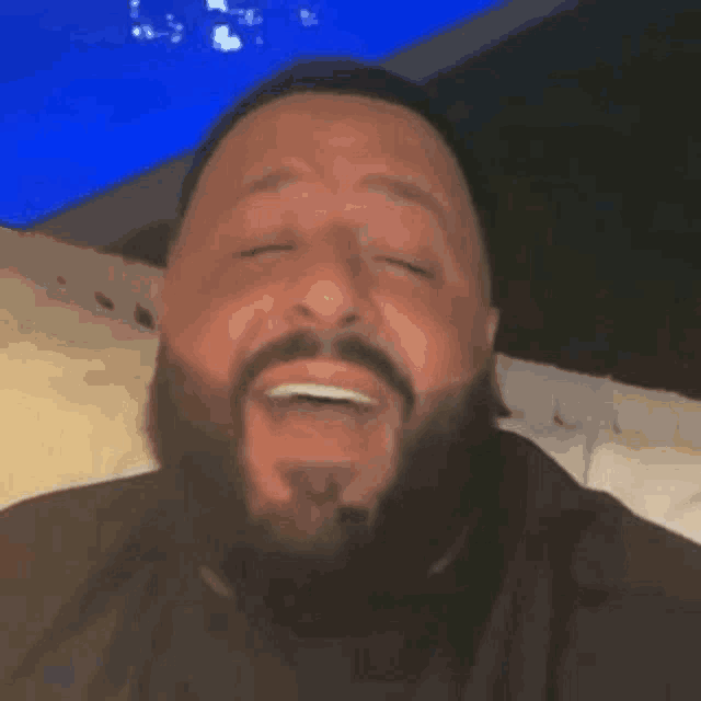 a man with a beard is making a funny face with his eyes closed .