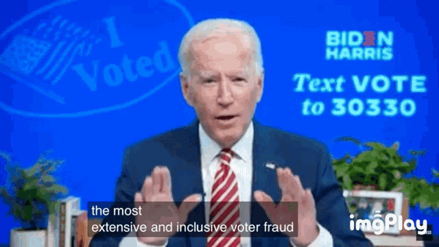 a man in a suit and tie is giving a speech in front of a biden harris sign