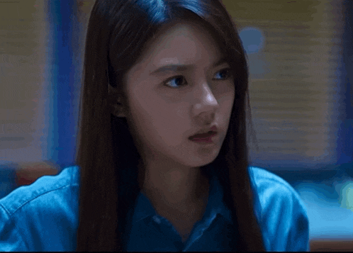 a woman with long hair and a blue shirt is looking at the camera