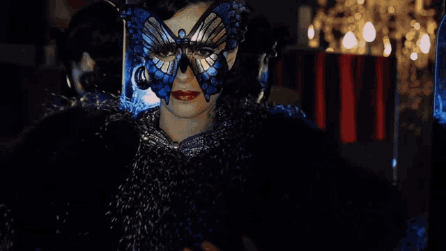a woman wearing a blue butterfly mask and a black fur coat