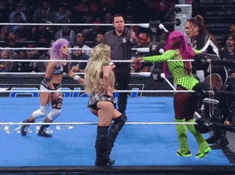 a woman in a green outfit is standing in a wrestling ring with other women