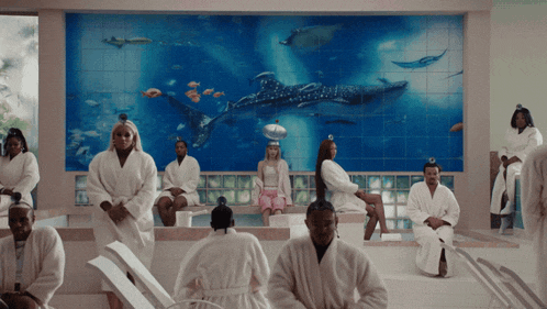 a group of people in bathrobes sitting in front of a whale shark mural