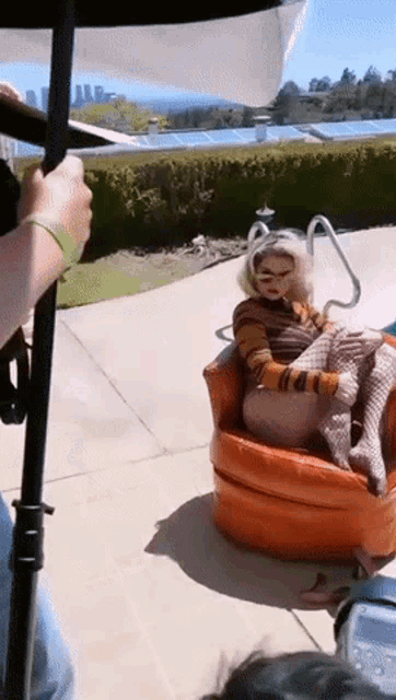 a woman is sitting in an orange chair next to a swimming pool