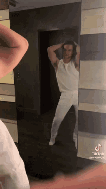 a man in a white shirt is standing in front of a mirror