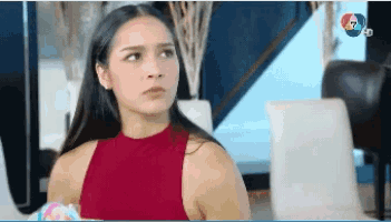 a woman in a red tank top is sitting in a chair