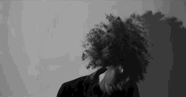a woman with curly hair is standing in front of a white wall .