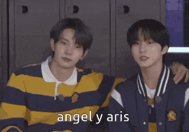 two young men are hugging each other in a locker room with the words `` angel y aris '' written on the bottom .
