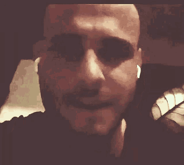 a man covering his mouth with his hand in a dark room