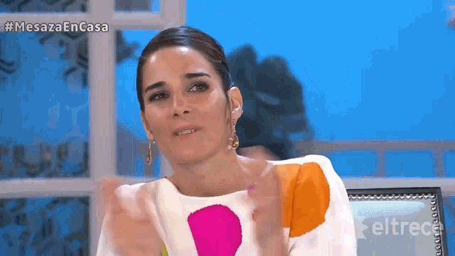 a woman sitting in front of a screen that says mesaza en casa on it