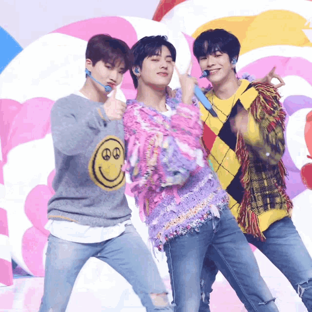 three young men are posing for a picture with one wearing a sweater with a smiley face