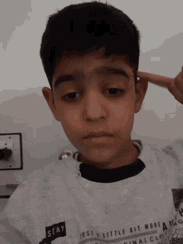 a boy wearing a white shirt that says stay