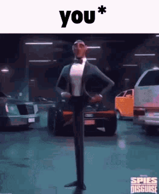 a man in a tuxedo and bow tie is standing in a garage with cars .