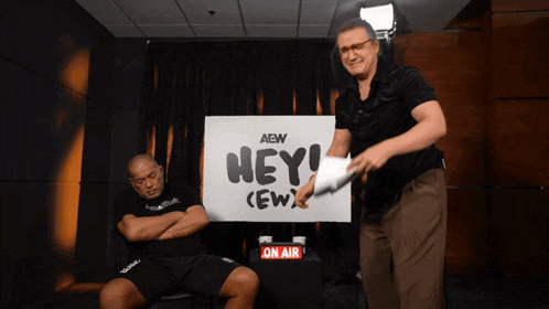 a man sitting in front of a sign that says hey
