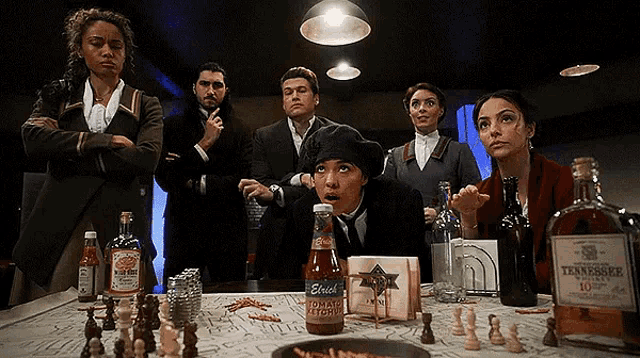 a group of people are gathered around a table with a bottle of erich tomato ketchup on it