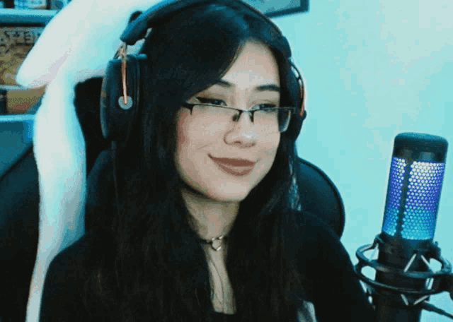 a woman wearing glasses and headphones looks at the camera
