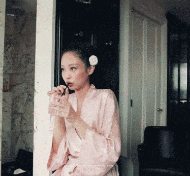 a woman in a pink robe drinks from a glass