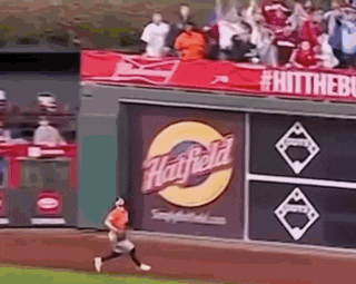 a baseball player is running on the field in front of a wall with a budweiser ad on it .