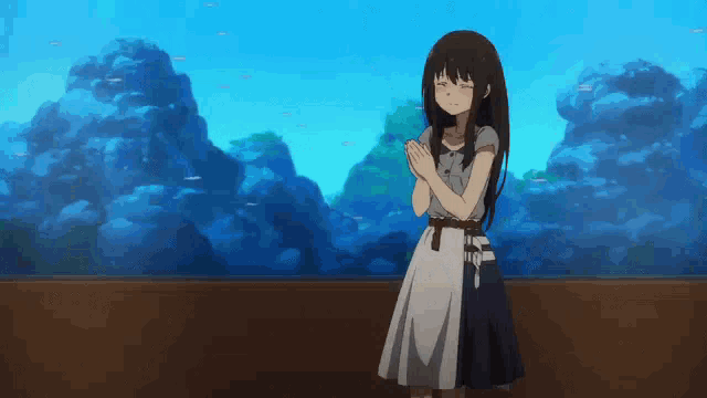 a girl in a dress is standing in front of an aquarium with fish in it .