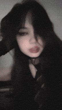 a girl with long black hair and a choker on her neck is making a funny face .