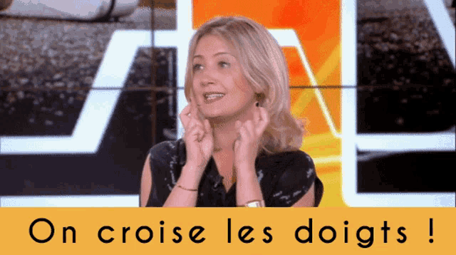 a woman is smiling in front of a sign that says on croise les doigts !