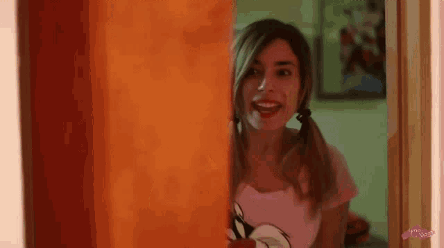 a woman with pigtails is standing in a doorway wearing a pink shirt with mickey mouse on it