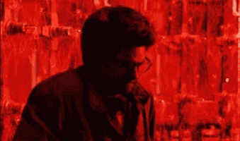 a man wearing a gas mask is talking on a phone in front of a red wall .