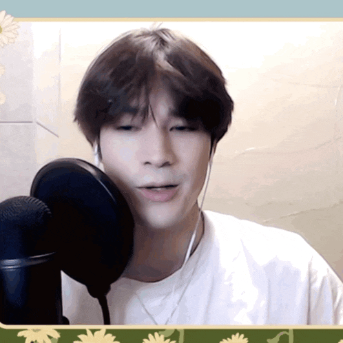 a man is singing into a microphone with a flower border