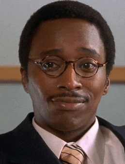 a man wearing glasses and a suit and tie is smiling