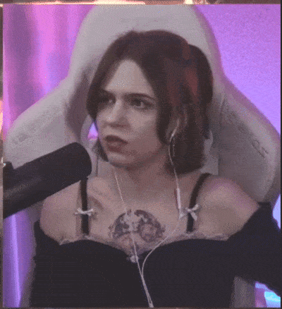 a woman with a tattoo on her chest is sitting in a chair with headphones on .